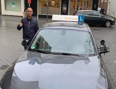 Geslaagde leerling Thao bij de lesauto van Autorijschool JongeLeeuw